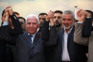 Head of the Hamas government Ismail Haniyeh (right) and senior Fatah official Azzam Al-Ahmed (left) raise their hands together at a news conference that announced a unity agreement between the rival Palestinian factions in Gaza City on April 23, 2014. Credit: Abed Rahim Khatib/Flash90.